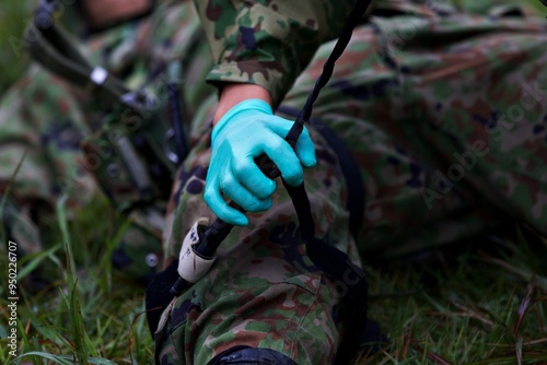 A person in a green glove is holding a black object photo