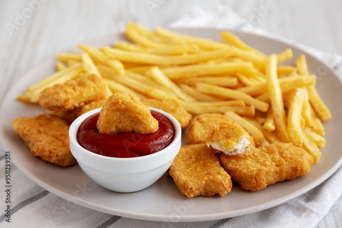 Fried Chicken Nuggets with French Fries on a Plate, side view.