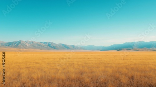 A vast golden grass field stretches into the distance, leading to a majestic mountain range under a clear blue sky.