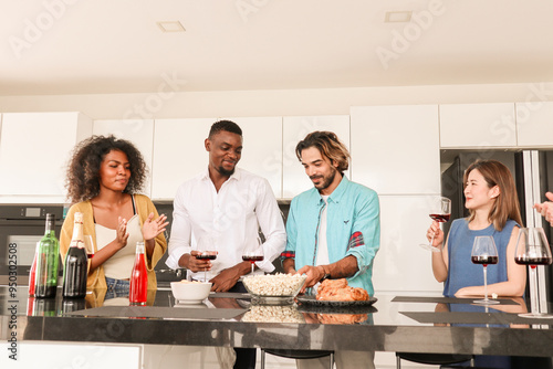 Multi-ethnic friends and family enjoy celebrating quality time together indoor. People raising and clinking glasses with red wine. Celebration concept with friends and family.