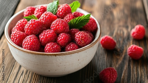 A bowl filled with freshly picked raspberries, their vibrant red hue contrasting with the white ceramic bowl, set on a wooden table