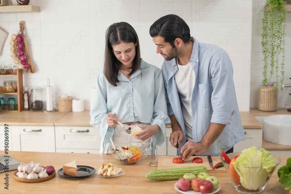 Happy couple preparing food at home, young couple cutting vegetables together at kitchen counter Happy couple preparing food at home, young couple cutting vegetables together at kitchen counter
