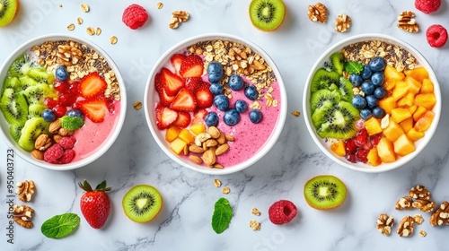 Colorful smoothie bowls topped with fresh fruits, nuts, and seeds on a marble background, top view