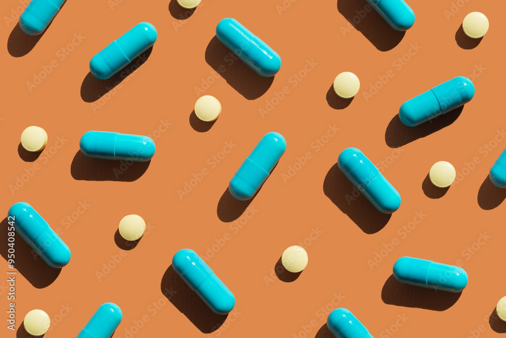 Pattern of blue and yellow pills on orange background. Creative tablets concept Pattern of blue and yellow pills on orange background. Creative tablets concept