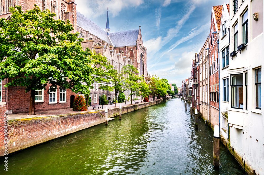 Church of Our Lady on Pottenkade street and historic buildings border a canal, in the old center of Dordrecht, the Netherlands.