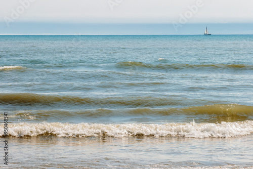 Looking out over Lake Michigan on a mid-August morning, a lone sailboat enjoys the solitude as it moves across the horizon offshore at Harrington Beach State Park, Belgium, Wisconsin photo