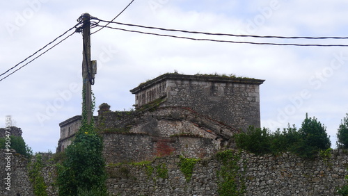 Des ruines d'un château fort médiéval, sous un ciel nuagueux, avec des lierres poussant de partout sur les murs, la nature reprenant ses droits, vestiges historiques hispaniques, rustique et ancien photo