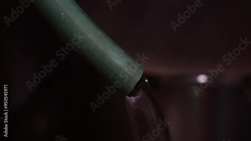Water flowing from a green pipe in the dark.