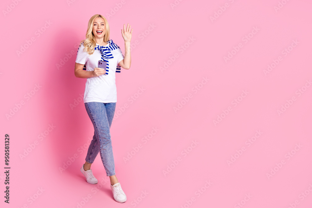 Full length photo of lovely young lady walking wave hand hi hold gadget dressed stylish white garment isolated on pink color background Full length photo of lovely young lady walking wave hand hi hold gadget dressed stylish white garment isolated on pink color background