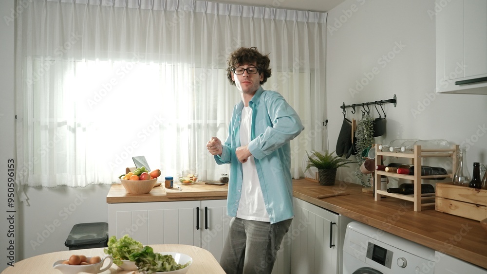 Happy father move to music while cooking food and prepare lunch at modern kitchen. Active dad dancing to song while making healthy food or salad surrounded with vegetable and kitchenware. Pedagogy. Happy father move to music while cooking food and prepare lunch at modern kitchen. Active dad dancing to song while making healthy food or salad surrounded with vegetable and kitchenware. Pedagogy.