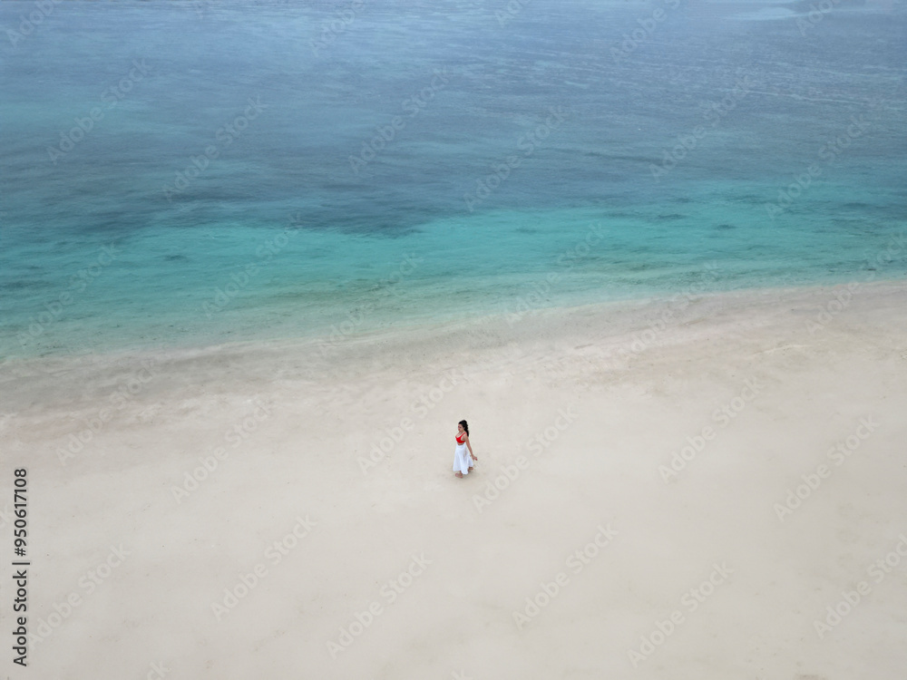 Woman in white dress walking on a secluded Mauritius beach Woman in white dress walking on a secluded Mauritius beach