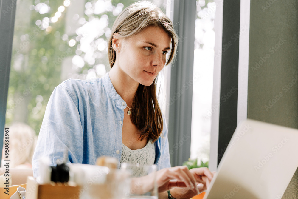 Focused freelancer woman working remotely from cafe on laptop computer Focused freelancer woman working remotely from cafe on laptop computer