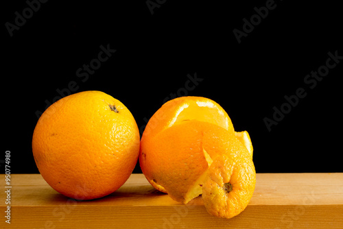 Ripe peeled oranges on a wooden shelf, isolated on black background.