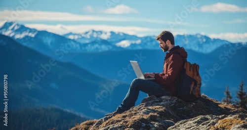 A young man works on a laptop while sitting at the top of a mountain. This concept represents the digital nomad lifestyle and the ability to work remotely or travel using the internet.
