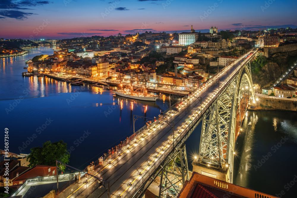 Fototapeta premium View of illuminated Porto city and Douro river and Dom Luis bridge I from famous tourist viewpoint Miradouro da Serra do Pilar in evening twilight. Porto, Vila Nova de Gaia, Portugal