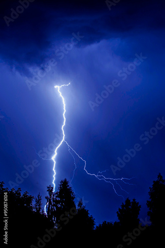 beautiful lightning during a thunderstorm at night in a forest that caused a fire, against a dark sky with rain