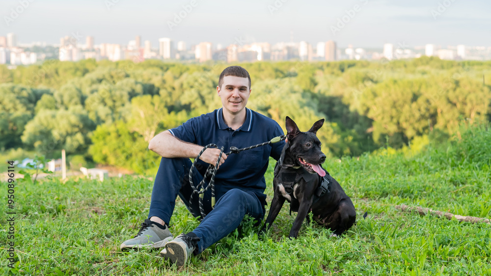 Caucasian man sitting with pit bull terrier on green lawn. Caucasian man sitting with pit bull terrier on green lawn.