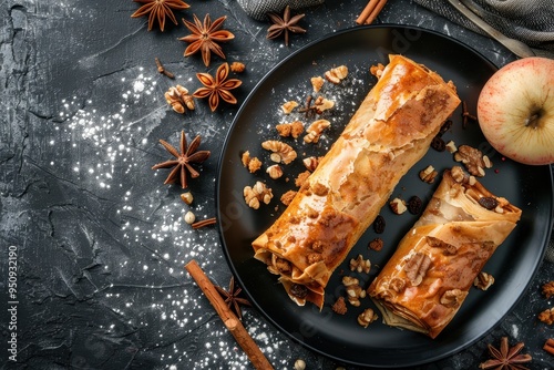 Apple strudel with caramelized apples nuts and raisins served on a black plate photo