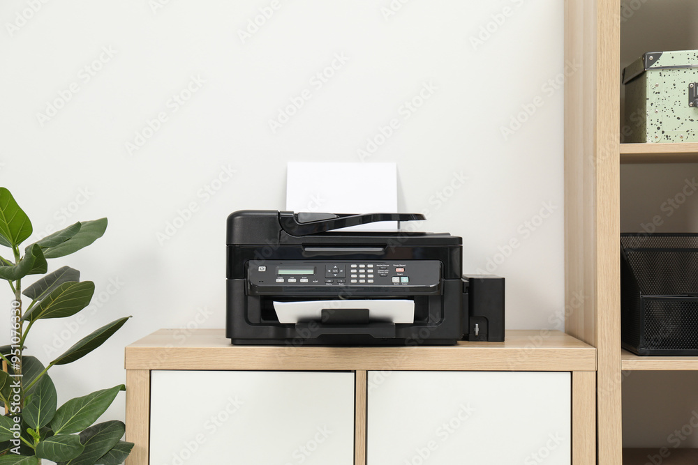 Modern printer with paper on wooden nightstand in office
