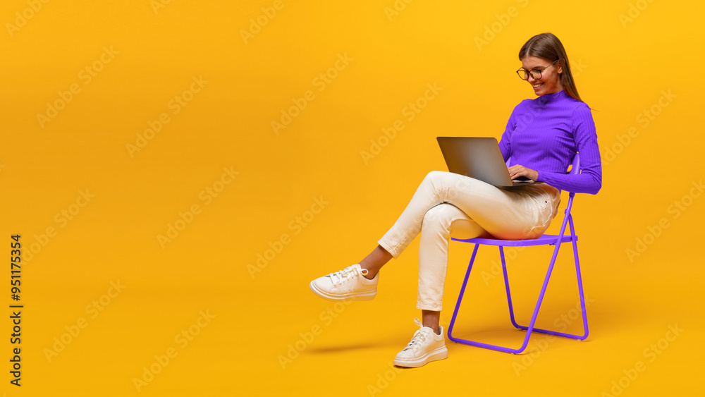 © Damir Khabirov - Portrait of woman working on laptop sitting on chair isolated on yellow banner background