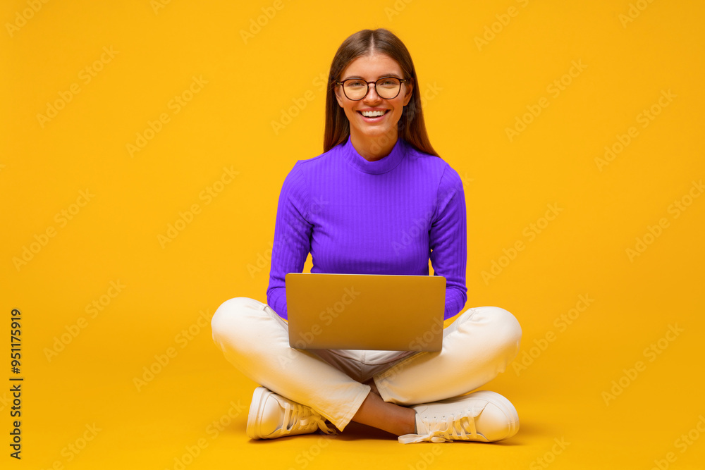 Portrait of woman on floor using laptop, playing video game, surfing internet on yellow background Portrait of woman on floor using laptop, playing video game, surfing internet on yellow background