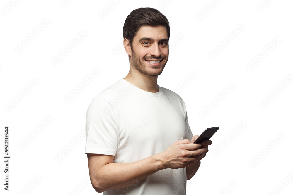 Young man looking and smiling at the camera with cheerful expression while texting to friend, using mobile phone Young man looking and smiling at the camera with cheerful expression while texting to friend, using mobile phone