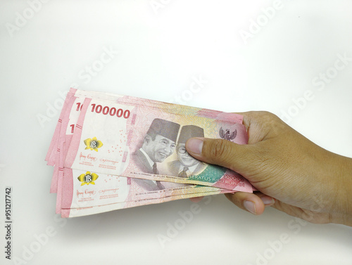 A man's hand is holding one hundred thousand Indonesian banknotes. Cash payment concept. Indonesian rupiah currency (Rp. 100,000 One Hundred Rupiah) on a white background