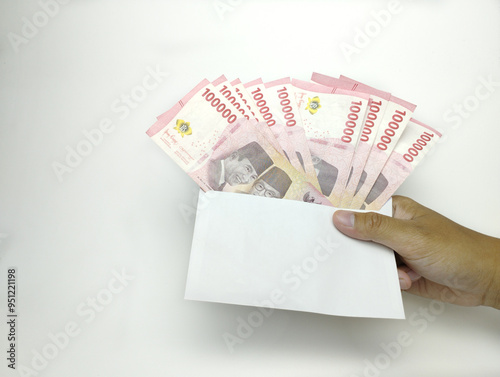 A man's hand is holding one hundred thousand Indonesian banknotes in envelope. Cash payment concept. Indonesian rupiah currency (Rp. 100,000 One Hundred Rupiah) on a white background