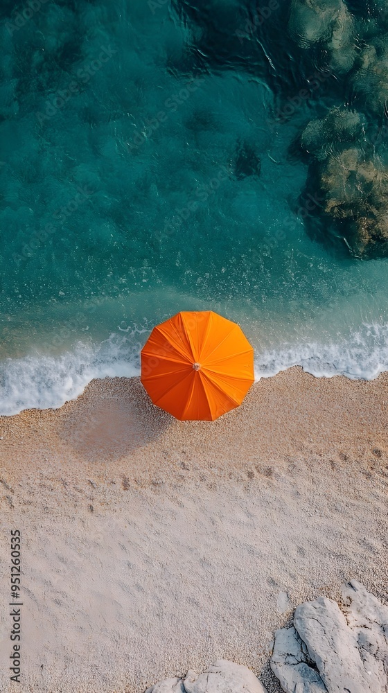 Naklejka premium Tranquil Overhead View of Vibrant Beach Umbrella on Serene Coastal Landscape