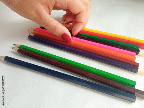 A woman takes a colored pencil from a pile of pencils. Stationery for school. Preparing for school. Learning to draw.