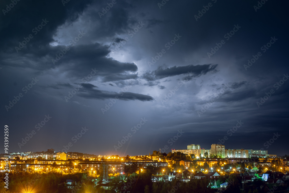 Fototapeta premium Lightning strikes in the night city among the menacing black clouds. Storm and thunderstorm