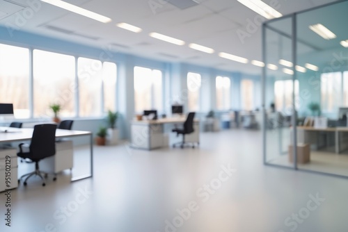 A blue blurred office interior featuring a desk with a laptop and computer, complete with a chair, monitor, keyboard, and other workspace essentials