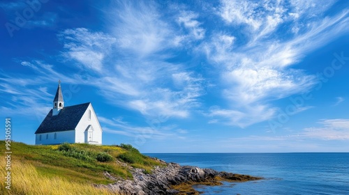 A picturesque church standing on a hill by the ocean, with a clear blue sky and scattered clouds overhead, creating a tranquil coastal scene.