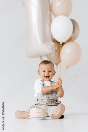 Canvas Print Happy laughing baby boy is sitting next to a birthday cake and balloons