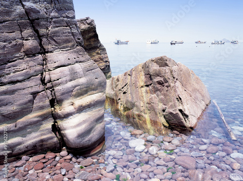 Sinan-gun, Jeollanam-do, South Korea - August 1, 2006: Summer view of pebble and rock on beach against moored fishing boats on the sea at Hongdo Island  photo