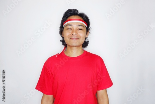 Portrait of an Indonesian man with long hair with a headband and red shirt celebrating Indonesian Independence Day with high nationalism on an isolated white background