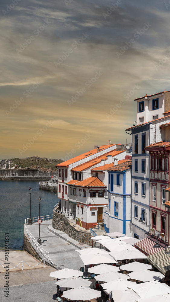 Obraz premium Disparo vertical de la hermosa villa pesquera de Cudillero en el litoral del mar Cantábrico, norte de España. Con cielo editado