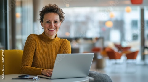 Smiling German woman working on her laptop in a sleek, contemporary office with high-tech gadgets and a bright atmosphere