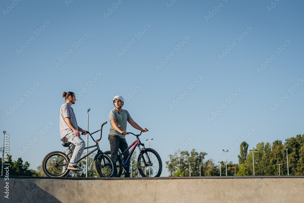 Obraz premium Two athletes having rest after riding at skatepark during summer morning day