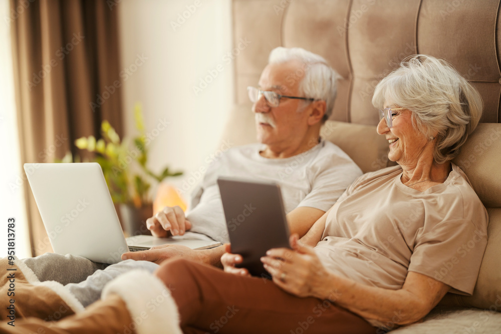 Happy senior couple sitting in bedroom and using technologies. Happy senior couple sitting in bedroom and using technologies.