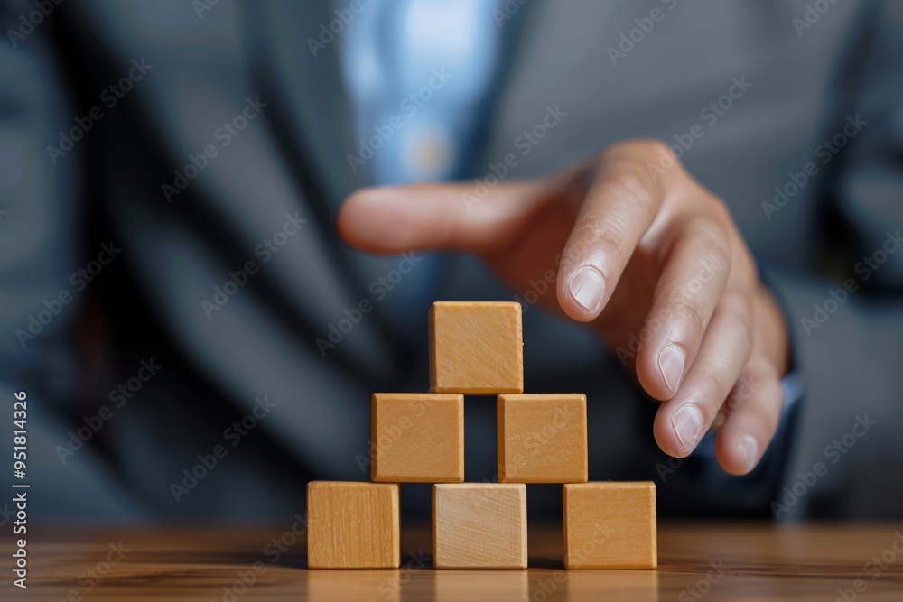 Businessman Stacking Wooden Block on Top of Pyramid of wooden blocks Businessman Stacking Wooden Block on Top of Pyramid of wooden blocks
