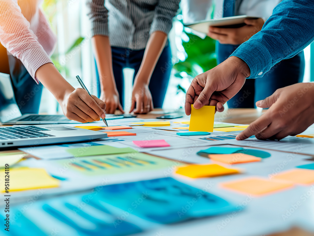 Close-up of team brainstorming with sticky notes and documents on a desk. Close-up of team brainstorming with sticky notes and documents on a desk.