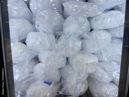 Plastic bags filled with ice cubes for sale inside a commercial chiller photo