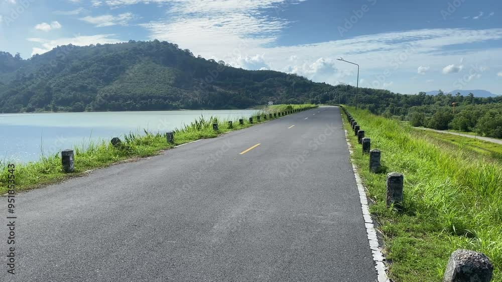 Empty road path at dam panning shot on a sunny day mountain blue sky tree and forrest view. Landscape view