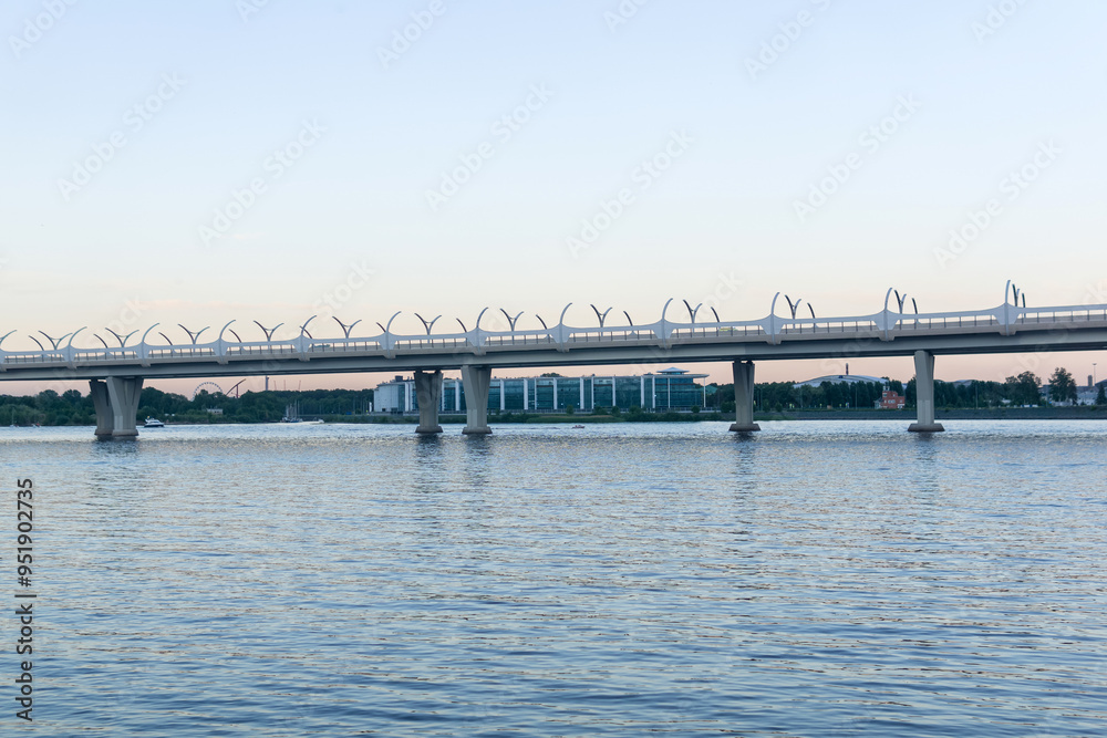 Fototapeta premium Evening cityscape with automobile bridge over river