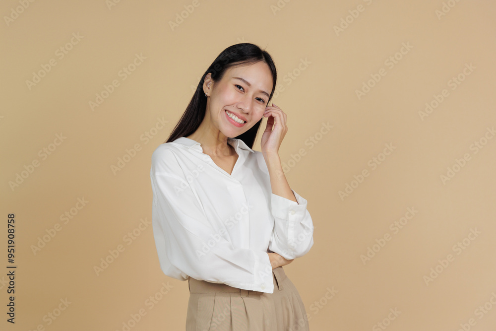 Smiling Woman Touching Face with Relaxed Expression, Beige Background Smiling Woman Touching Face with Relaxed Expression, Beige Background