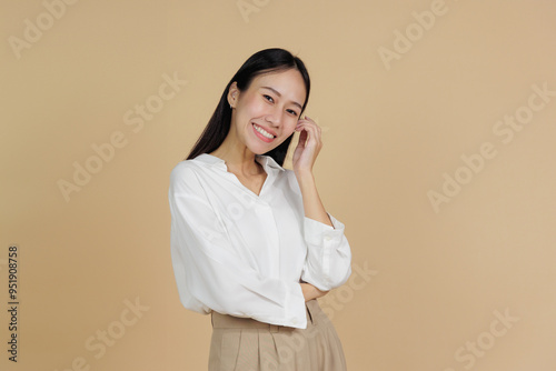 Smiling Woman Touching Face with Relaxed Expression, Beige Background