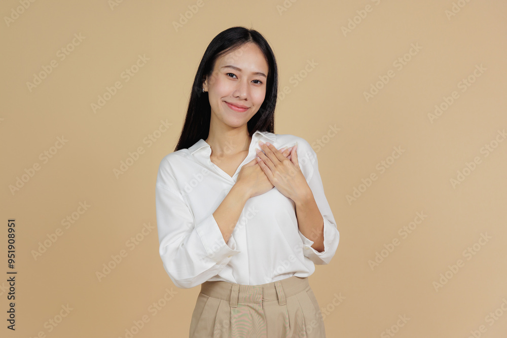 Grateful Woman with Hand on Heart, Expressing Thanks, Beige Background Grateful Woman with Hand on Heart, Expressing Thanks, Beige Background