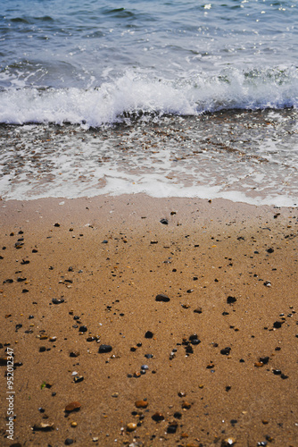 Sea Waves Crashing on Beach Sand with Stones and shells on the shore