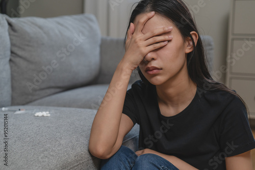 Anxiety drug addict asian young woman covering her face and sitting on the floor.